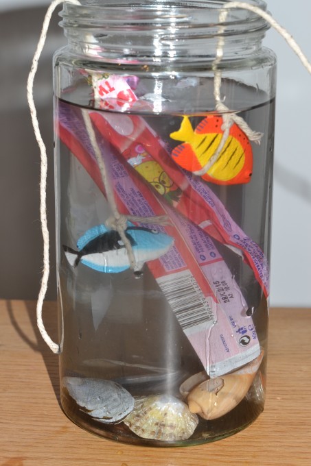 A glass vase filled with water and rubbish to demonstrate the effects of pollution to kids.
