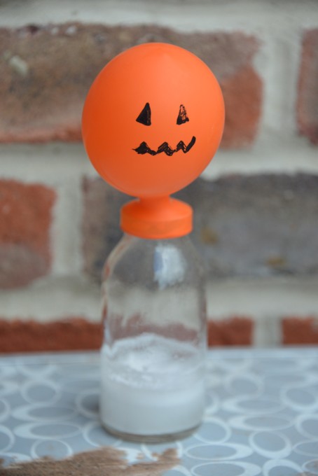 Balloon decorated to look like a pumpkin blown up on a jar - great experiment for Halloween